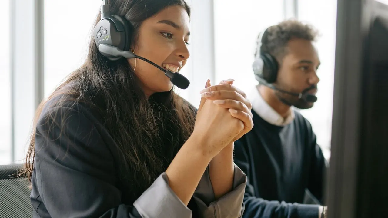Two agents wearing headsets answering calls in a modern office