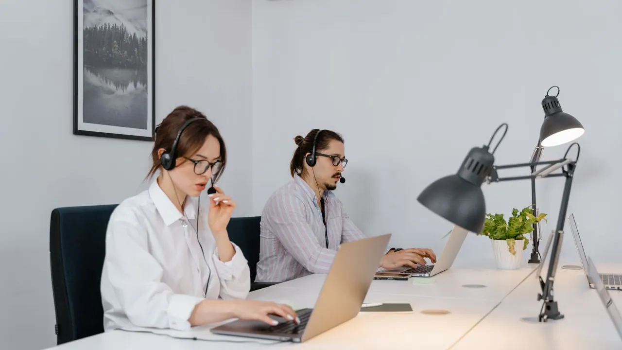Two agents at laptops with headsets handling customer calls