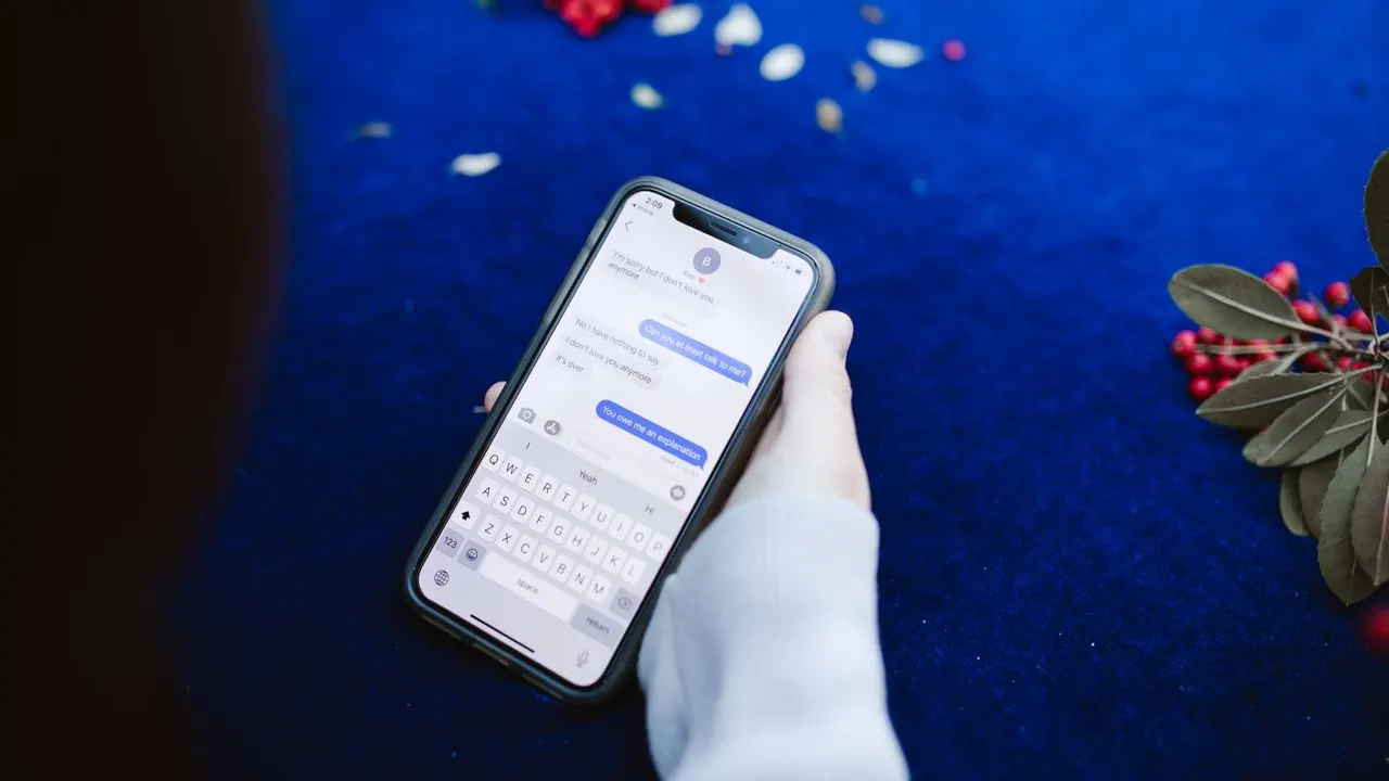 Hand holding a smartphone with a chat conversation on screen