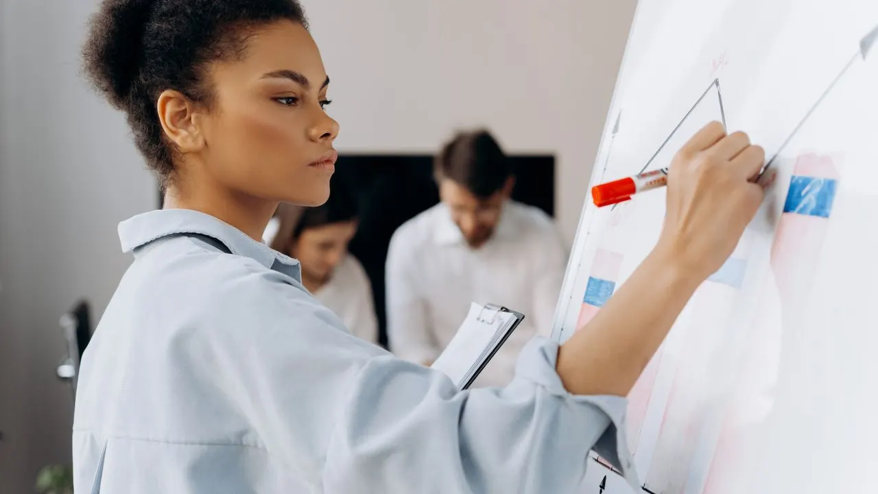 Professional sketching a strategy diagram on a whiteboard